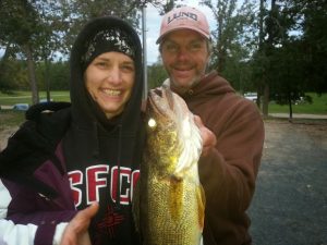 A man and woman hold up a fish they caught